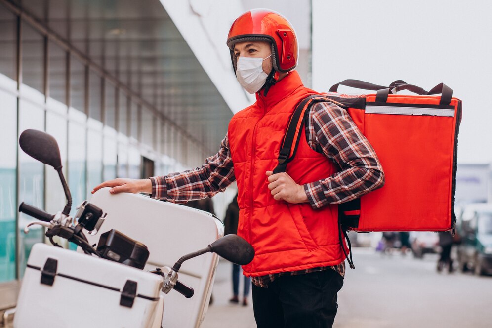 Delivery driver with red helmet and insulated bag, illustrating how a ghost kitchen works with food delivery. 