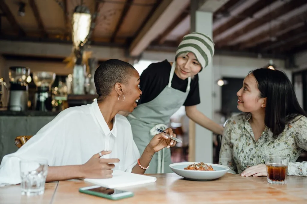 Women tasting food and interacting with restaurant staff